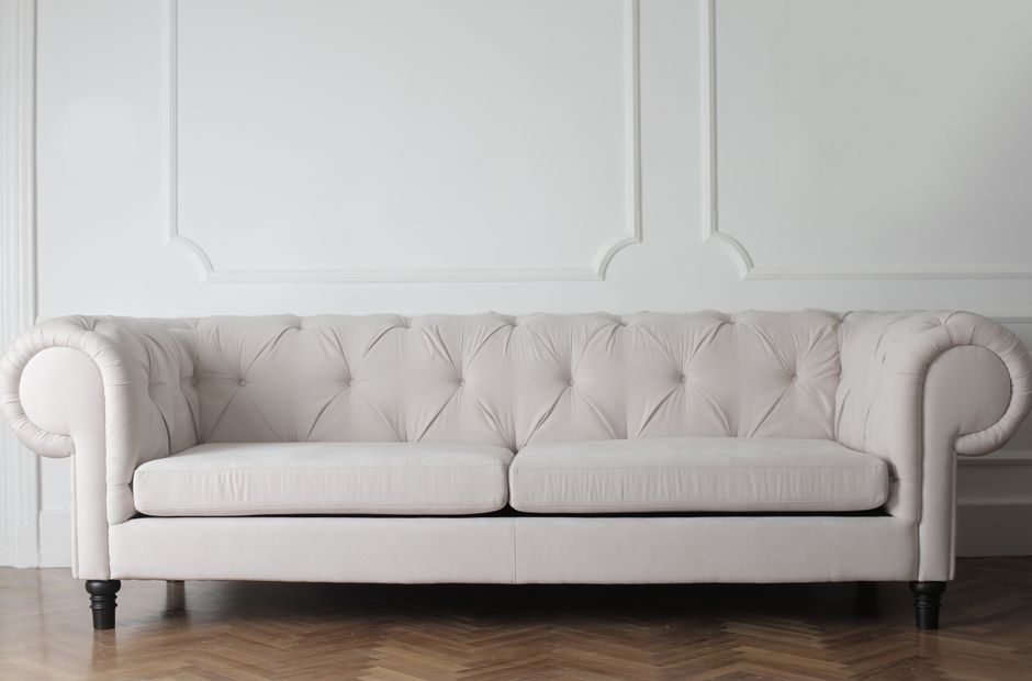 Luxurious white sofa in a modern minimalist interior with wooden flooring.